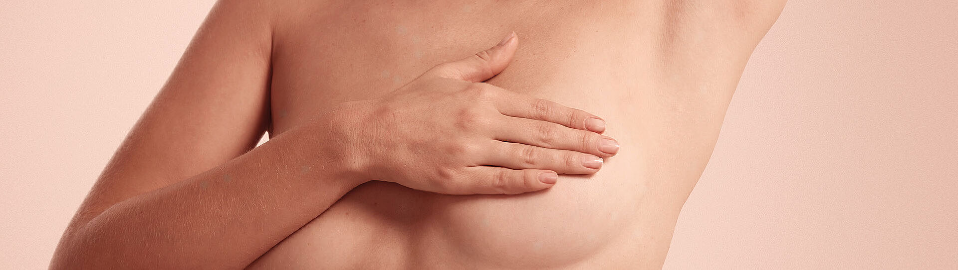 Una donna si sta toccando il petto contro uno sfondo neutro.